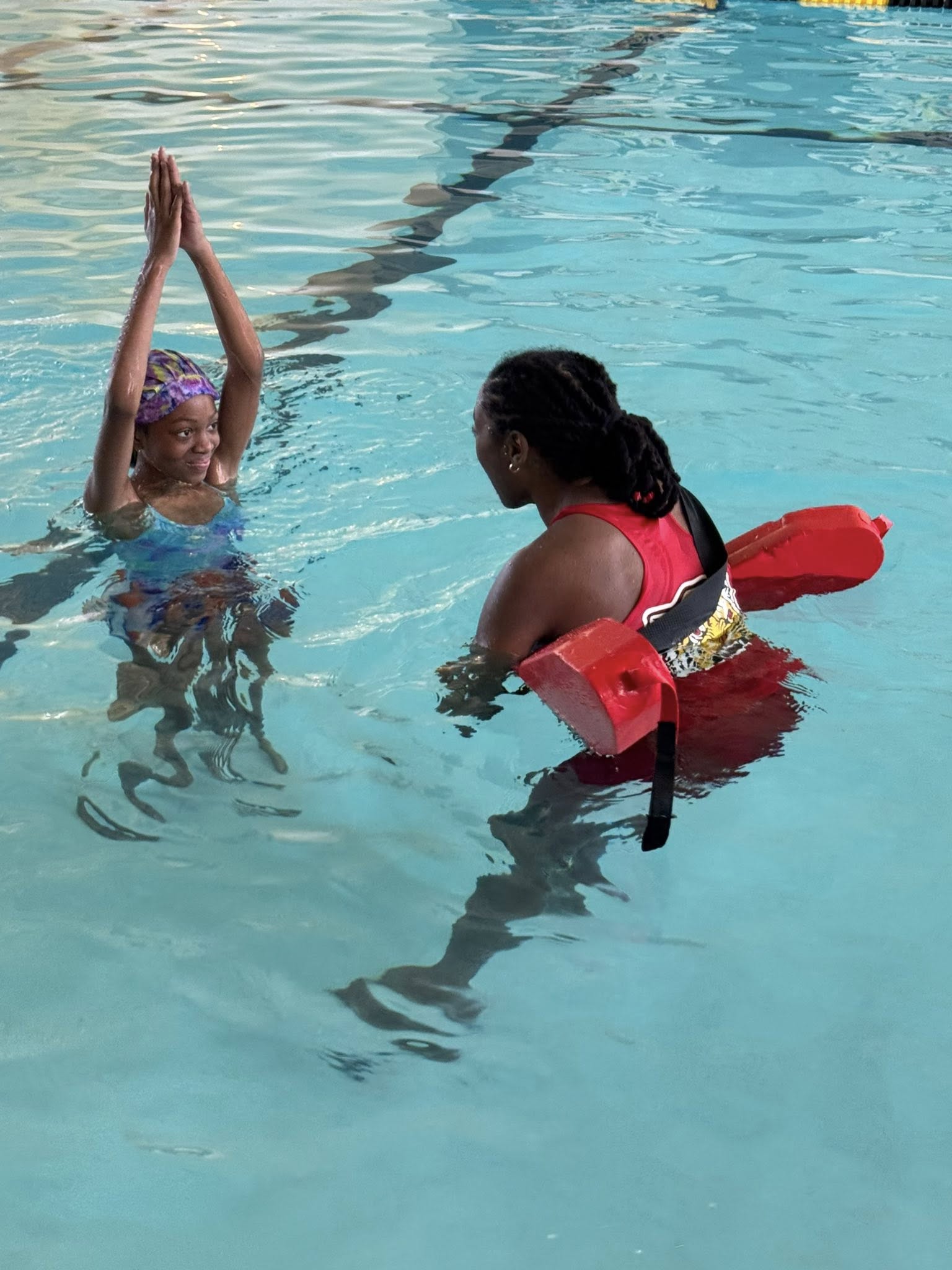 A girl and a woman standing in a pool.